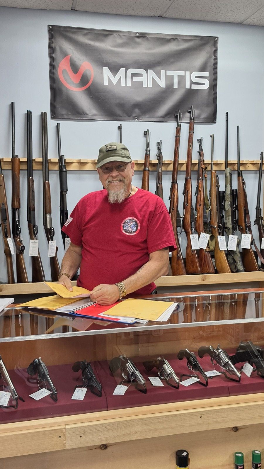 The counter where evaluations happen, used revolver case in front, long-gun wall behind